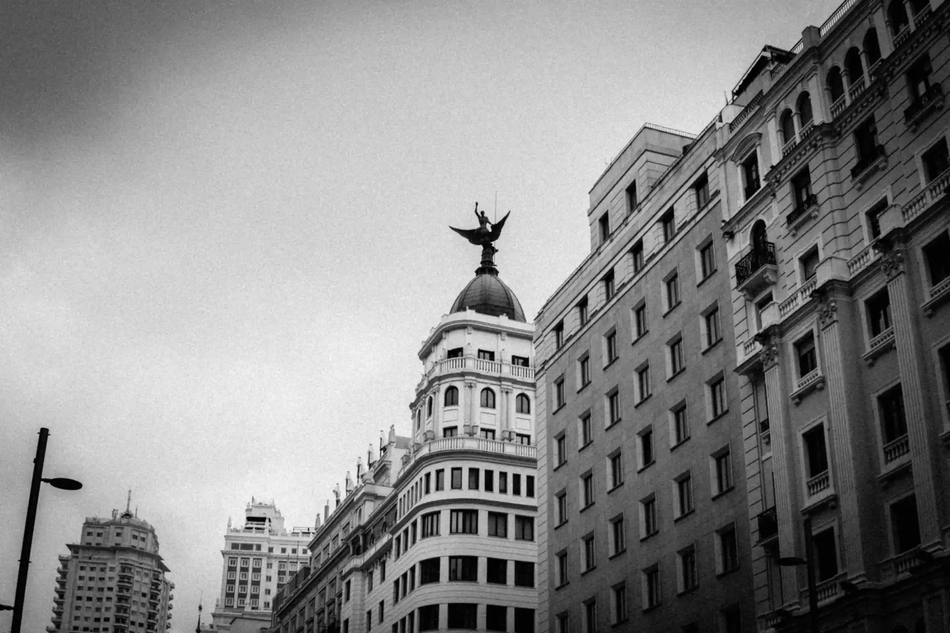 Edificios de la Gran Vía de Madrid en blanco y negro, con una estatua alada sobre la cúpula